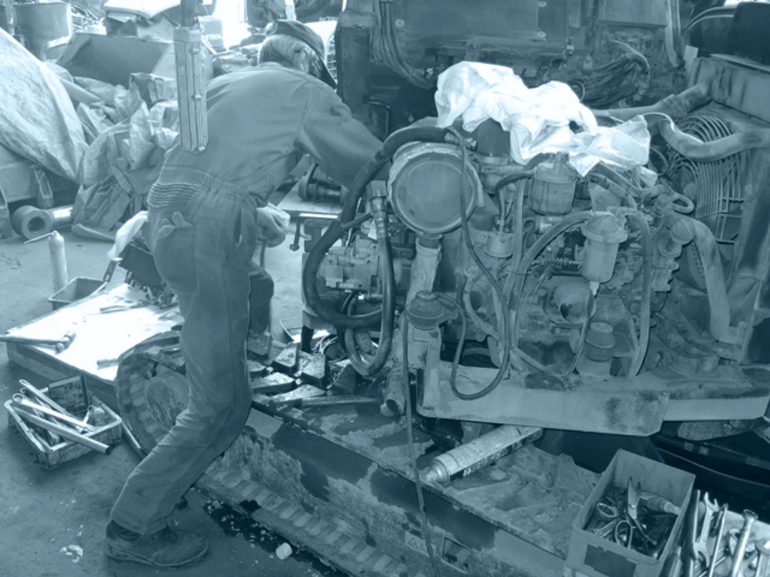 重機のエンジンを整備する作業員の写真
