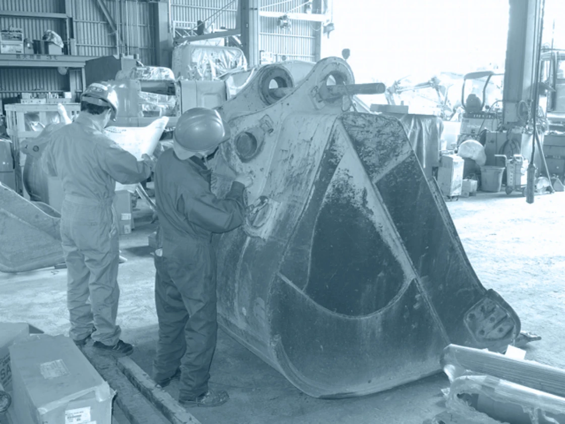 工場内で大型機械部品を点検する作業員の様子。