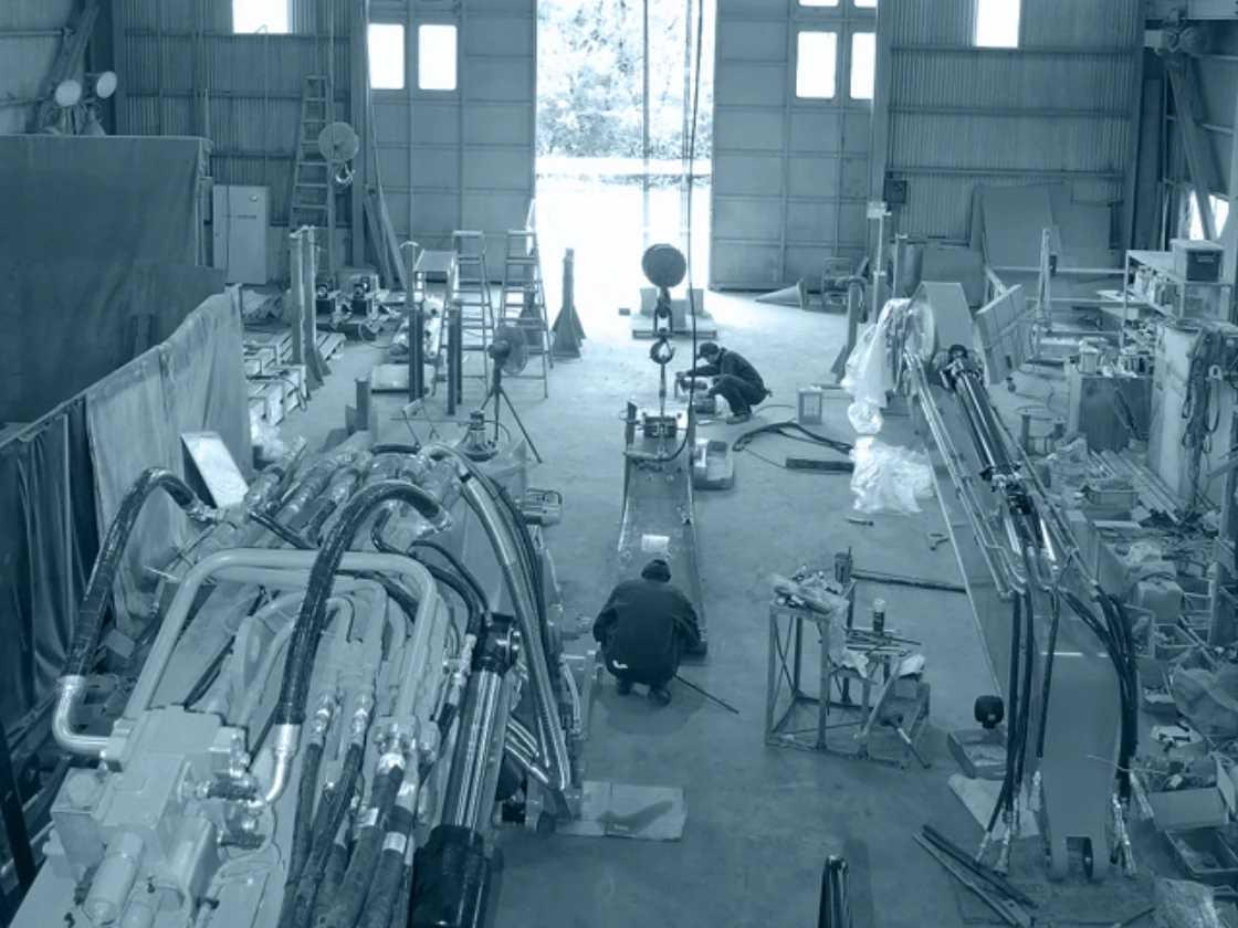 工場内で機械設備のメンテナンス作業を行う技術者たち。