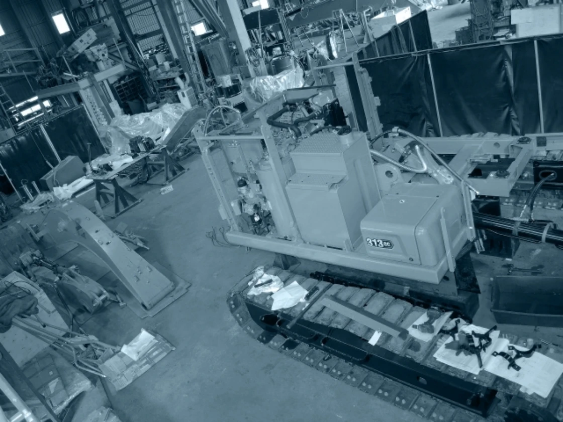 工場内で組み立て中の建設機械部品と装置